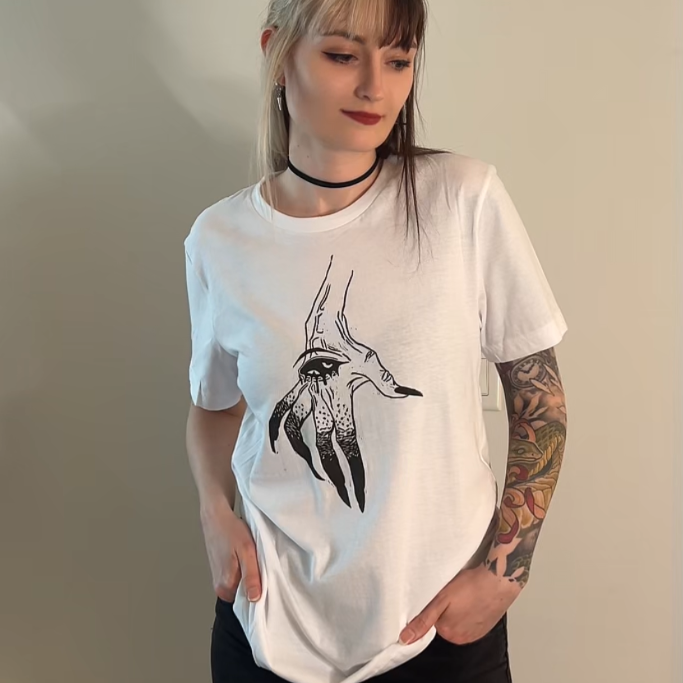 Person wearing a white t-shirt with a graphic design, standing against a plain wall.