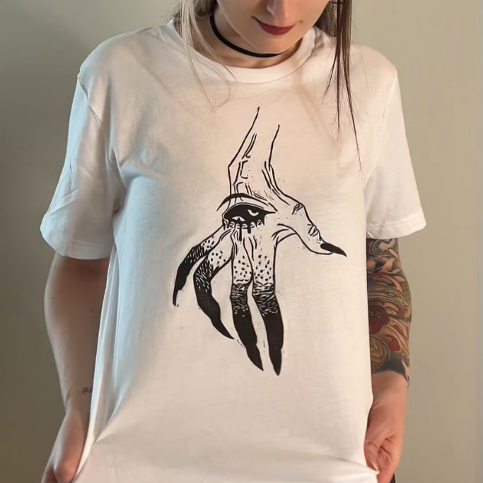 Person wearing a white t-shirt with a black graphic design on a plain background