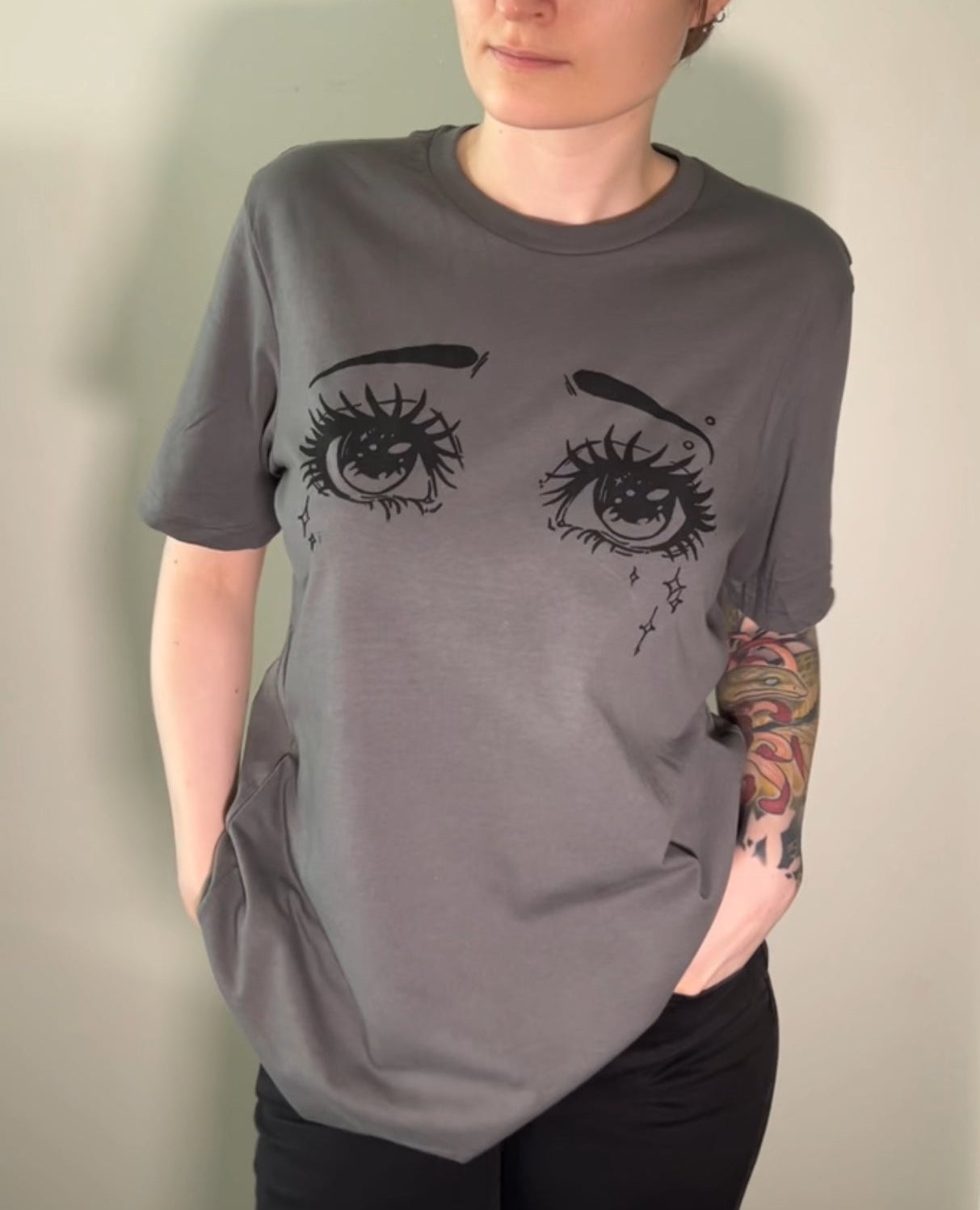 Person wearing a gray t-shirt with eye design against a plain background