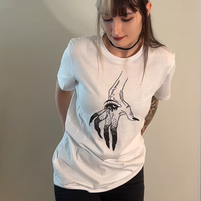 Person wearing a white t-shirt with a graphic design, standing against a plain wall.