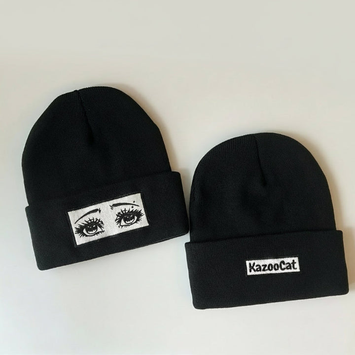 Two black beanies with eye design and 'KazooCat' logo on a white background