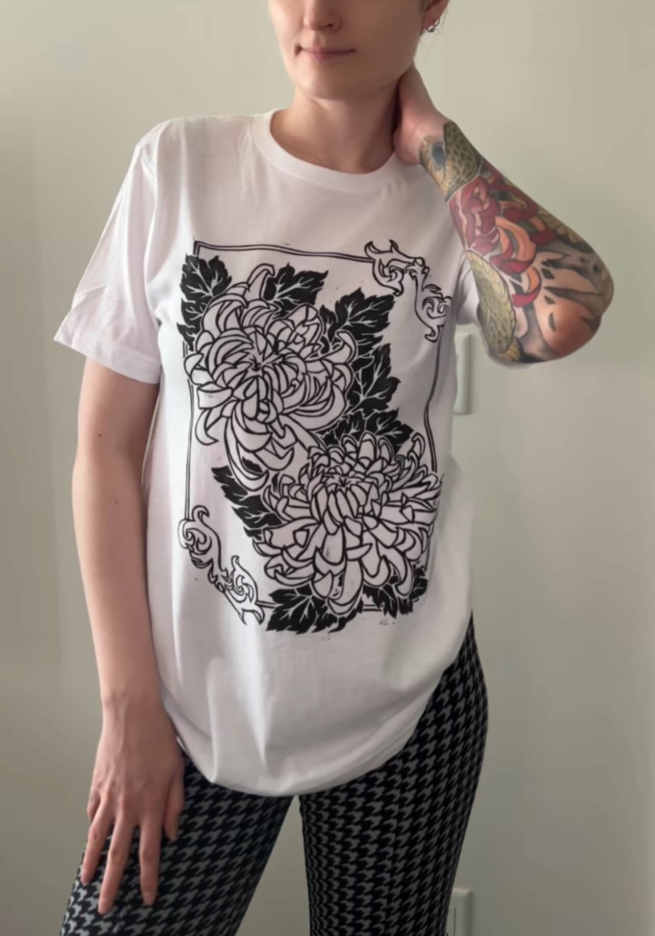 Person wearing a white t-shirt with black floral design against a plain background