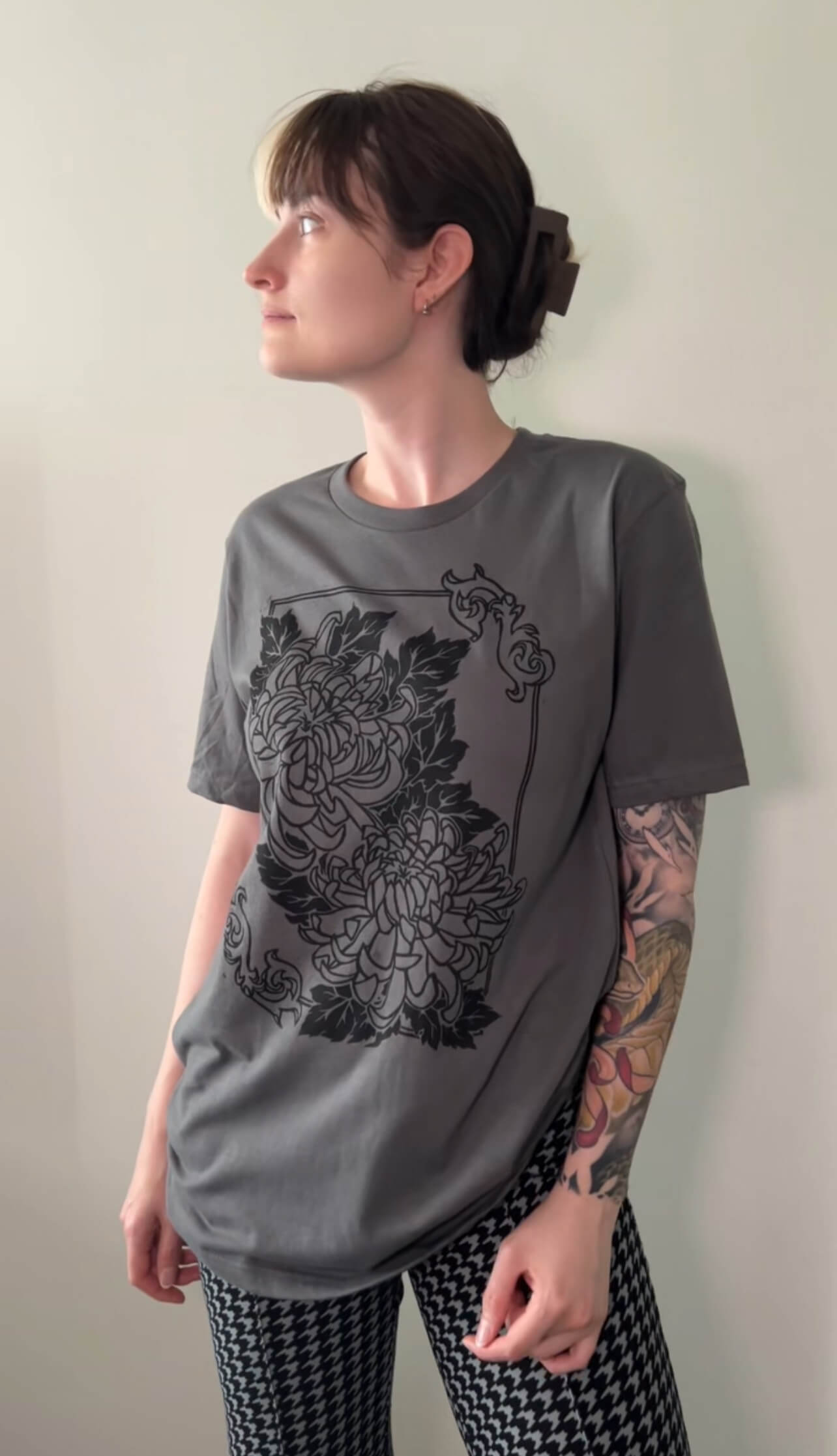 Person wearing a gray t-shirt with black floral design against a plain background